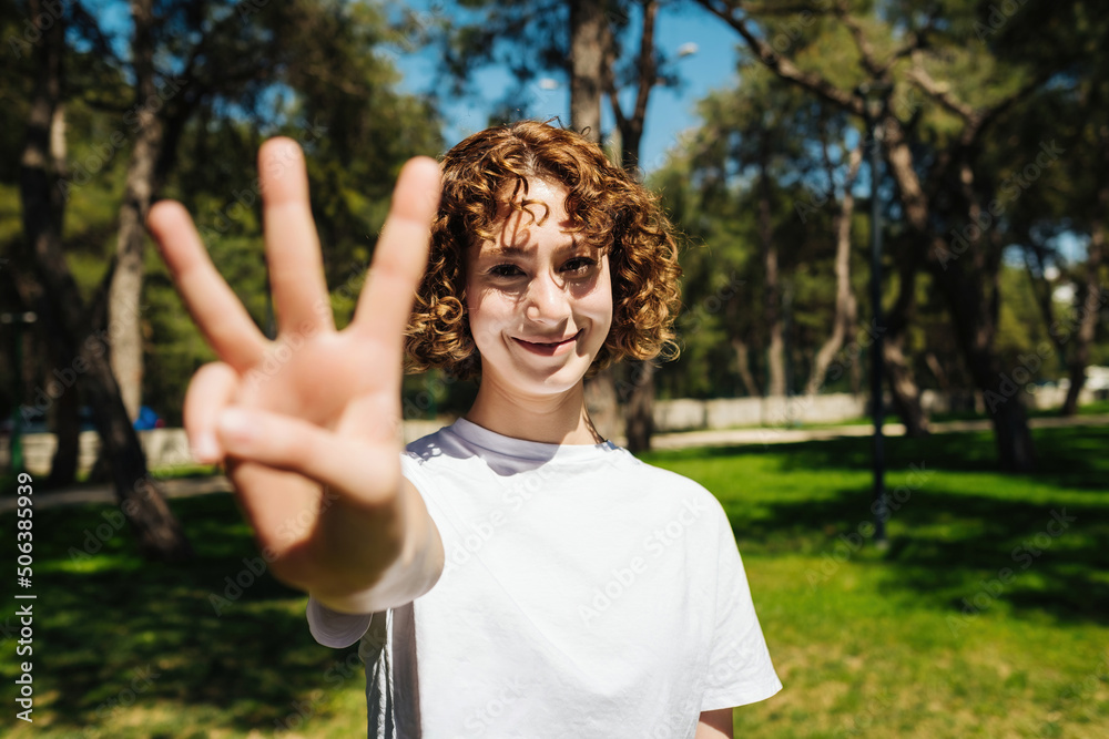 Young beautiful redhead woman wearing casual white tshirt showing and pointing up with fingers number three while smiling confident and happy.