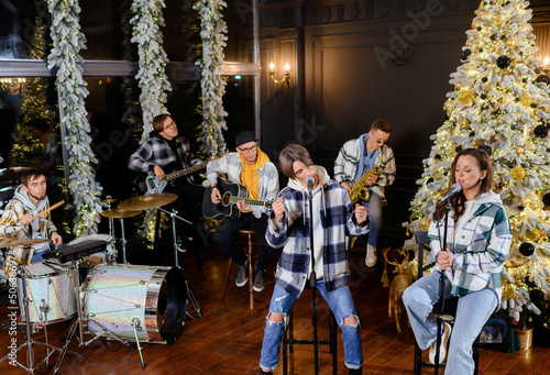 Young rock band sings and plays on the background of the Christmas tree New Year's songs