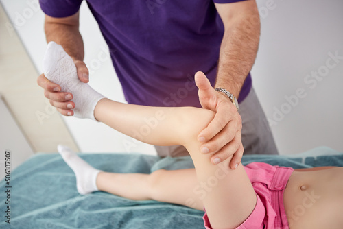 Pediatric orthopedist physiotherapist performs manipulative procedures with child leg in clinic. Medicine and healthcare concept