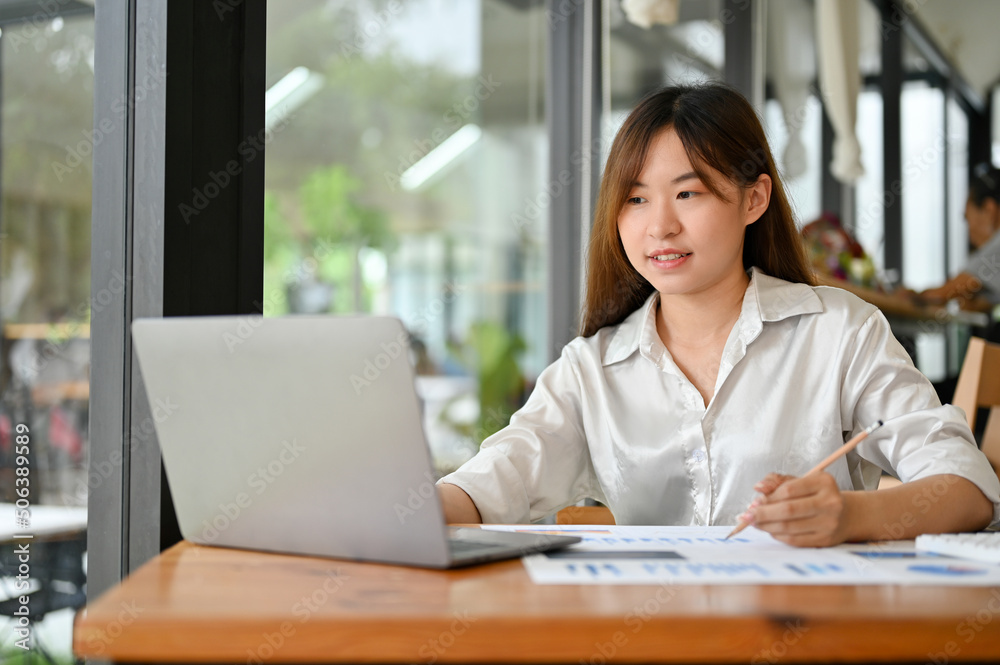 Female office worker using laptop computer, sitting in the coffee shop. remote working concept