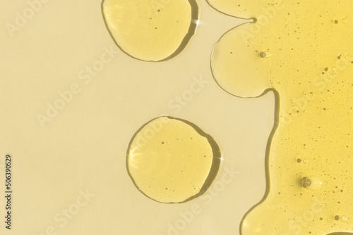 Drops of transparent cosmetic gel or serum yellow on a beige background. The concept of cosmetics or virus protection. Top view