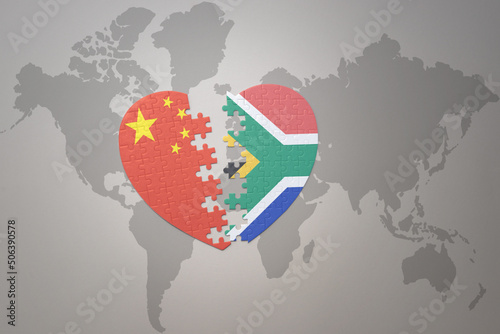 puzzle heart with the national flag of china and south africa on a world map background. Concept.