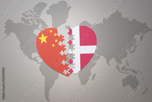 puzzle heart with the national flag of china and denmark on a world map background. Concept.