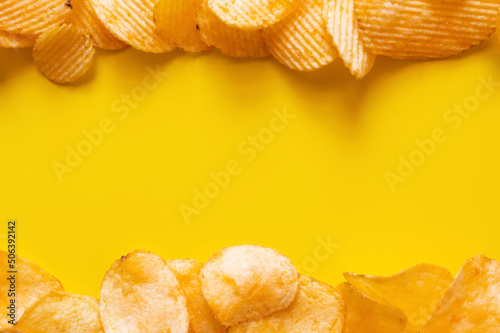 flay lay view of different salty and wavy potato chips on yellow photo