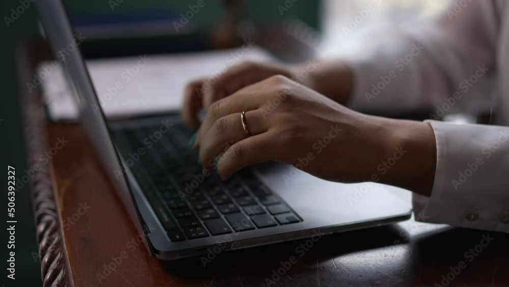 Close view of young businesswoman typing on laptop and sitting at table in modern office spbas. 4k Hands of American African female types text and uses computer, does work and sits at wooden desk in Close view of young businesswoman typing on laptop and sitting at table in modern office spbas. 4k Hands of American African female types text and uses computer, does work and sits at wooden desk in
