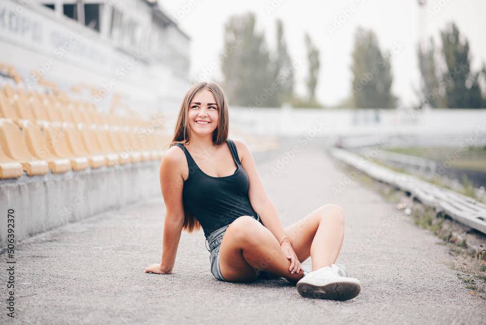 Portrait of a young girl on a summer evening who sits on the street in a free pose.