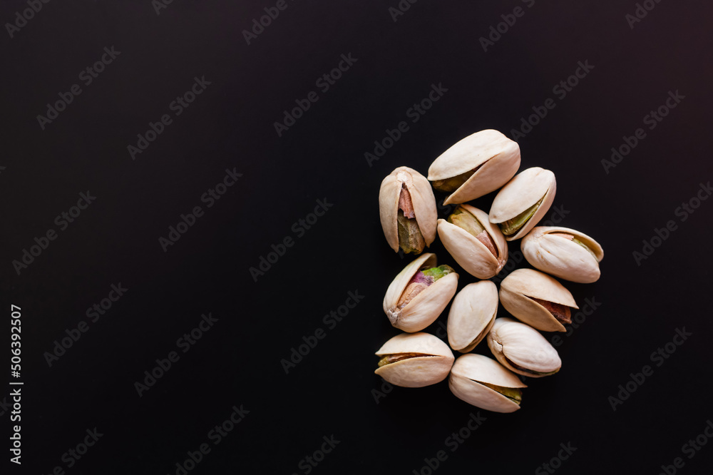 top view of cracked and salty pistachios isolated on black - obrazy, fototapety, plakaty 