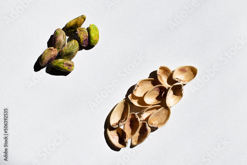 top view of organic and salty pistachios near nutshells on white background