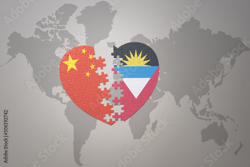 puzzle heart with the national flag of china and antigua and barbuda on a world map background. Concept.