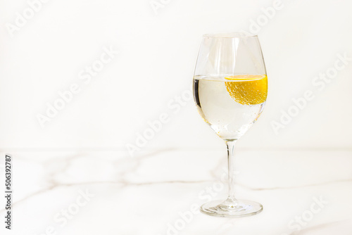 A glass of water with lemon on a light table for healthy life, energy, thermoregulation and normalization of digestion