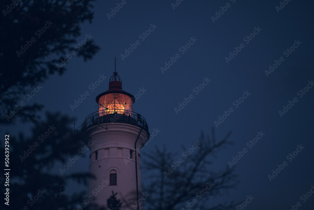 Lighthouse in the early morning hours through some branches. High quality photo