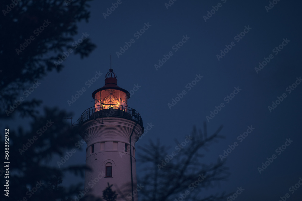 Lighthouse in the early morning hours through some branches. High quality photo Lighthouse in the early morning hours through some branches. High quality photo