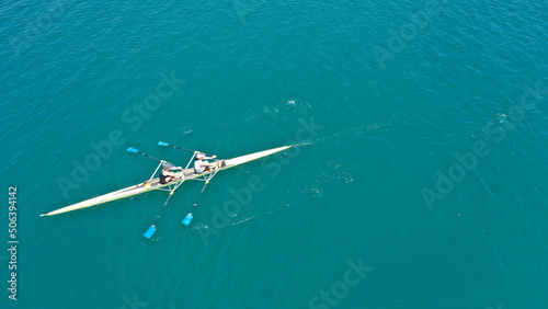 Aerial drone top down photo of sport canoe operated by team of young women in emerald sea waters