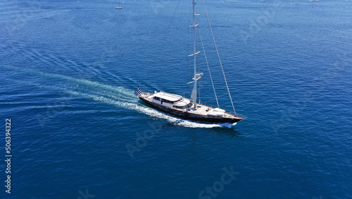 Aerial drone birds eye view photo of beautiful sailboat with blue sails cruising in the deep blue Aegean sea, Greece © aerial-drone