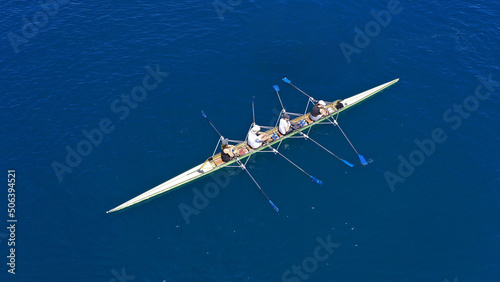 Aerial drone photo of sport canoe operated by team of young trained athletes in deep blue Aegean sea