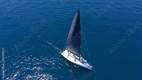 Aerial drone birds eye view photo of beautiful sailboat with blue sails cruising in the deep blue Aegean sea, Greece © aerial-drone