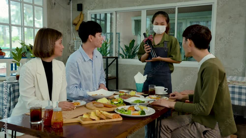 4K 50fps, A restaurant employee, holding a bottle of wine, introduced three close friends to the dining table, after they finished their meal. 4K 50fps, A restaurant employee, holding a bottle of wine, introduced three close friends to the dining table, after they finished their meal.