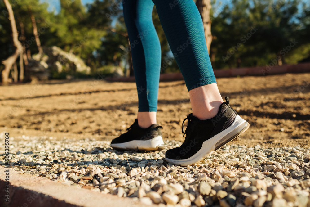 Young woman wearing blue pants and black shoes walking and running on nature green background. Health, exercise and outdoor cardio workout concept. Young woman wearing blue pants and black shoes walking and running on nature green background. Health, exercise and outdoor cardio workout concept.