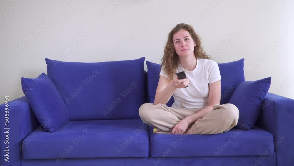 Caucasian woman sit on sofa. Change channels on TV. in front of the TV for long time. Depression. find smth interesting. Weekend in cozy house. laziness concept. Slacker. Lonely lotus on blue couch. Caucasian woman sit on sofa. Change channels on TV. in front of the TV for long time. Depression. find smth interesting. Weekend in cozy house. laziness concept. Slacker. Lonely lotus on blue couch.