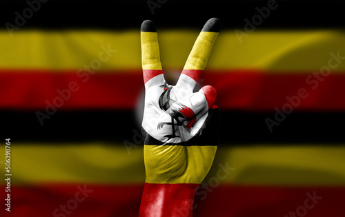 Hand making the V victory sign with flag of uganda photo