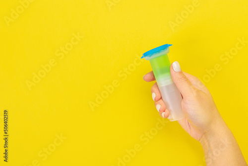 The housewife's hand holds a cleaning brush. Empty space for text or logo on a yellow background. Early spring or regular cleaning. Cleaning and cleaning concept. flat lay