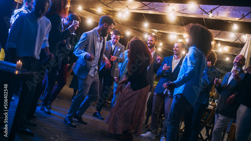 Beautiful Carefree Friends are Dancing Together and Celebrating an Evening Event at a Party . Diverse Multiethnic Young Adult People Have Fun at a Corporate Party in a Restaurant.