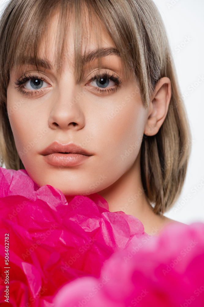 young woman with bangs and blue eyes near pink decorative flower isolated on white young woman with bangs and blue eyes near pink decorative flower isolated on white