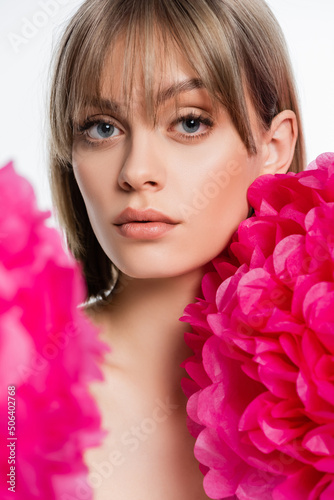 young woman with bangs near bright pink flowers isolated on white