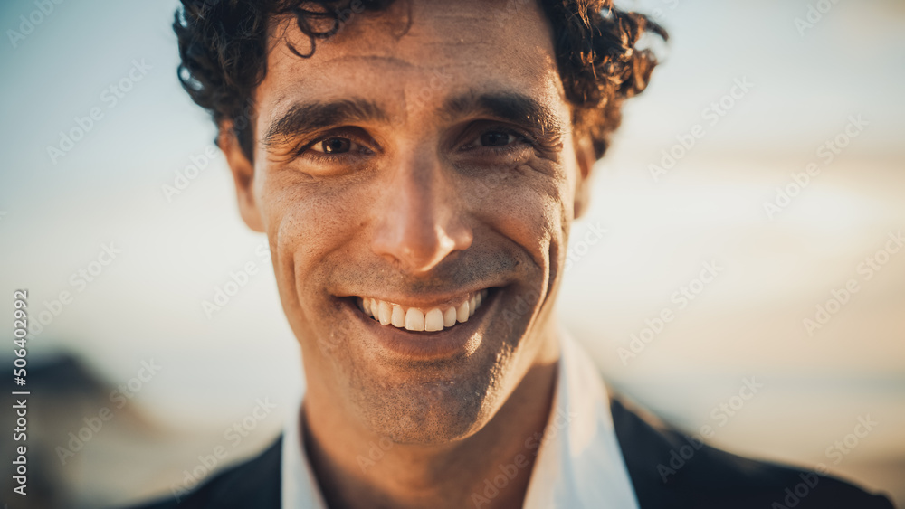 Close Up Portrait of a Happy Young Adult Male with Curly Hair and Brown Eyes Posing for Camera. Handsome Multiethnic Caucasian Male in a Suit Charmingly Smiling. Warm Color Edit. - obrazy, fototapety, plakaty 