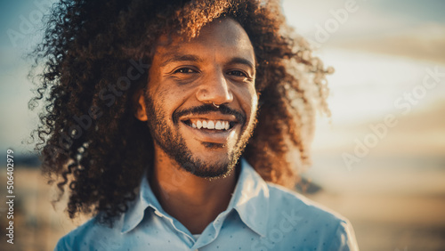 Close Up Portrait of a Happy Young Adult Male with Afro Hair and Nose Ring Piercing Posing for Camera. Handsome Diverse Multiethnic Black Male Smiling. Warm Color Edit. © Gorodenkoff