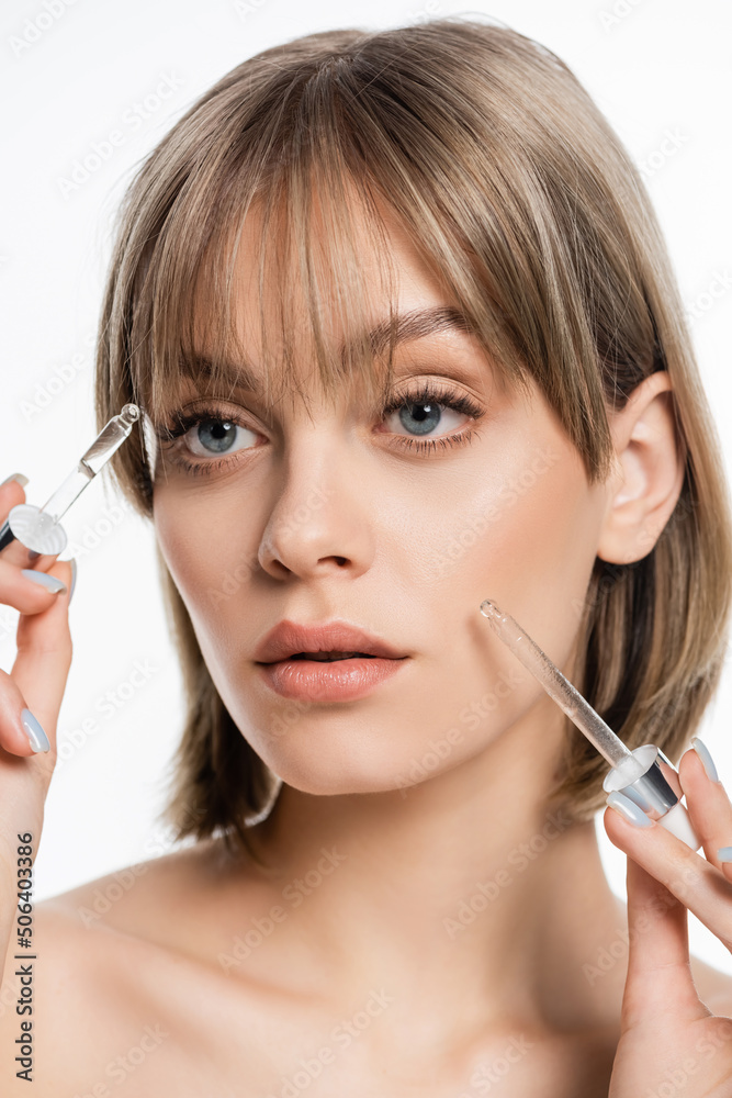 Fototapeta premium young woman with blue eyes applying serum with pipettes isolated on white