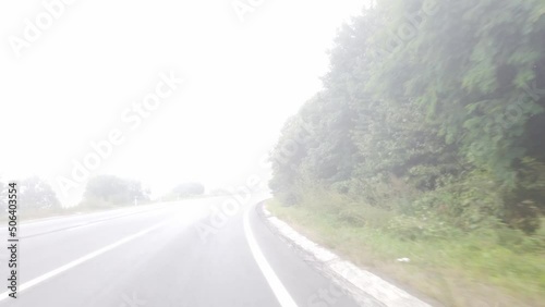 Trip on asphalt serpentine road in fog. Summer foggy landscape with winding highway, view from car window