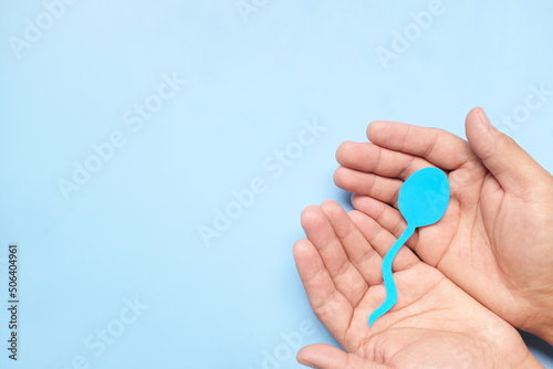Fotografía Top view of male hand holding sperm cutout in blue background