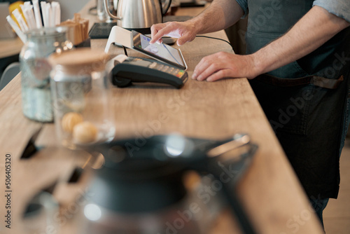 Close up of barista uses a digital tablet to take an order at a coffee shop