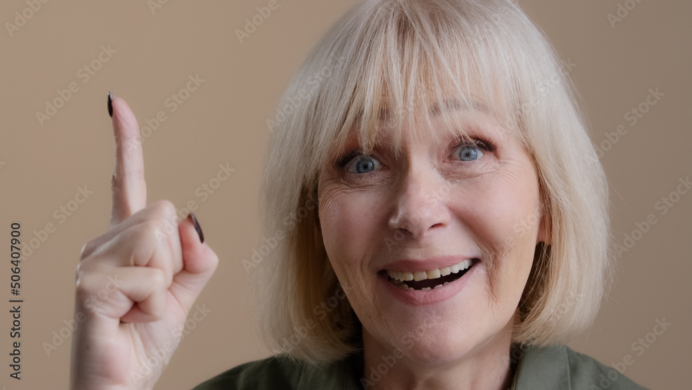 Studio shooting pensive mature old 60s Caucasian woman puzzled thinking planning remind deep in thoughts solves problem concentrate remembers comes up with idea finds solution raising index finger Studio shooting pensive mature old 60s Caucasian woman puzzled thinking planning remind deep in thoughts solves problem concentrate remembers comes up with idea finds solution raising index finger
