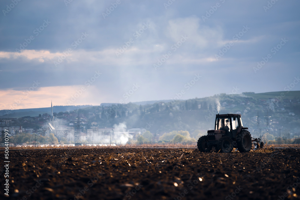 Fototapeta premium Tractors plowing fields in early spring