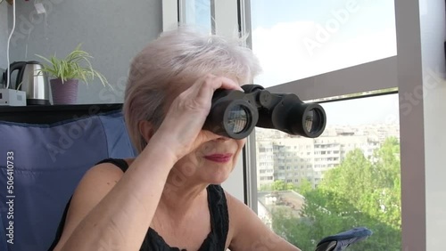 Elderly woman peeping through binoculars  photo