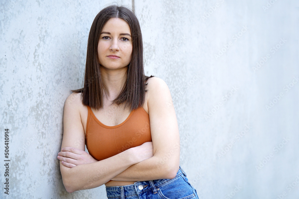 Young beautiful woman in summer clothes leans on a concrete wall for a portrait Young beautiful woman in summer clothes leans on a concrete wall for a portrait