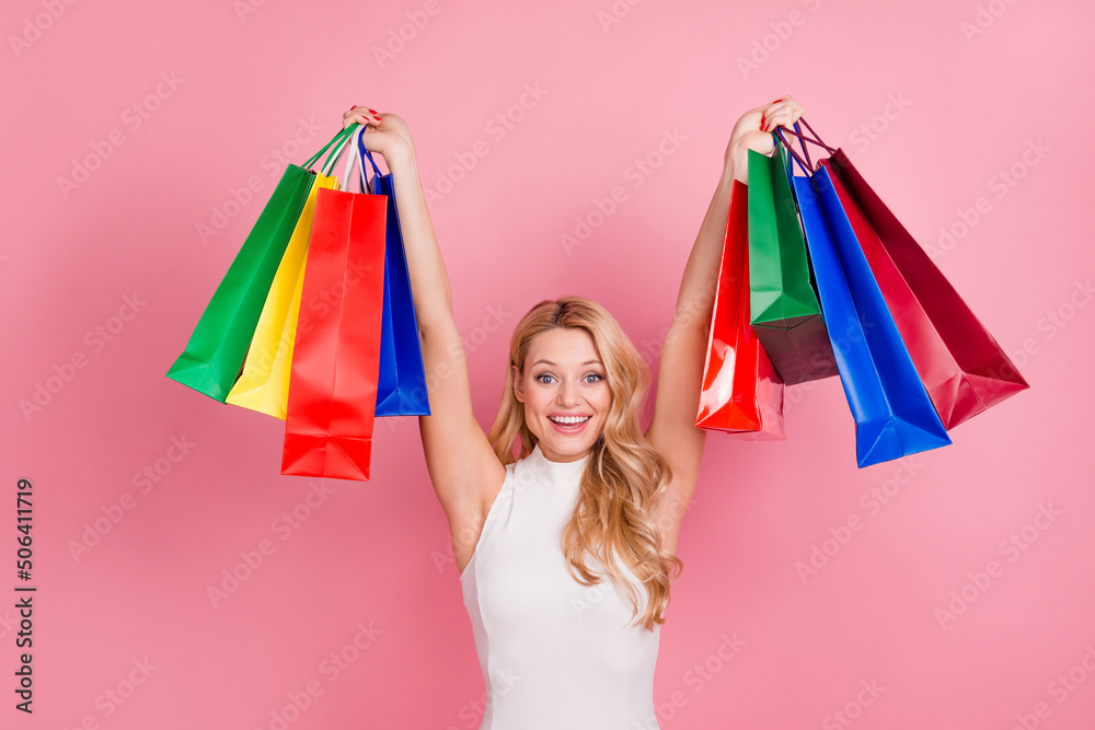 Portrait of delighted funky lady hands hold raise packages isolated on pink color background