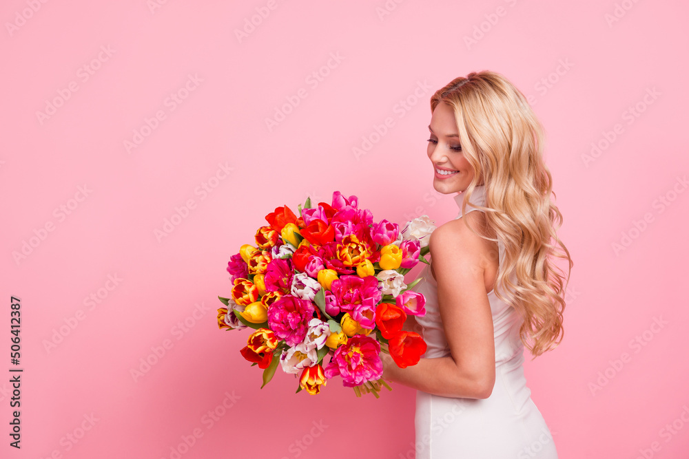 Photo of cheerful sweet woman wear white dress holding flowers bunch empty space isolated pink color background