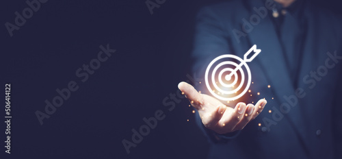 Businessman holding virtual dartboard and arrow with copy space for setup business objective target concept.