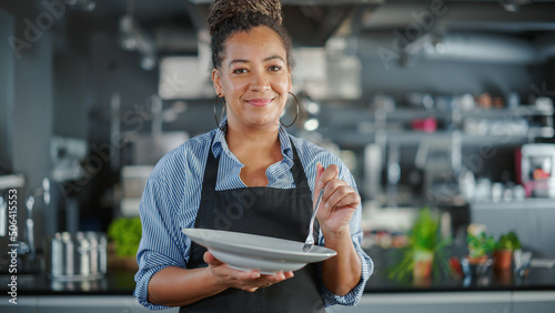 Billede på lærred Restaurant Kitchen: Portrait of Black Female Chef Preparing Dish, Tasting Food and Enjoying it