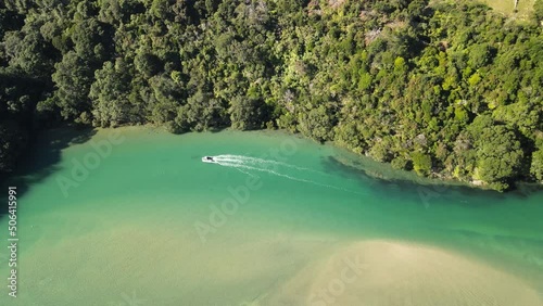 Boat driving down the turquoise waters of New Zealand's coromandel peninsula. photo