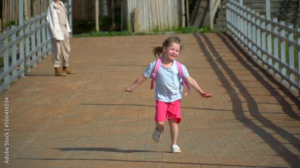 girl runs along pier on sunny day. beginning of holidays in a happy family. Enjoy vacation. Cheerful childhood. A small kid runs with a backpack on a sea beach. Traveling the world with children. girl runs along pier on sunny day. beginning of holidays in a happy family. Enjoy vacation. Cheerful childhood. A small kid runs with a backpack on a sea beach. Traveling the world with children.