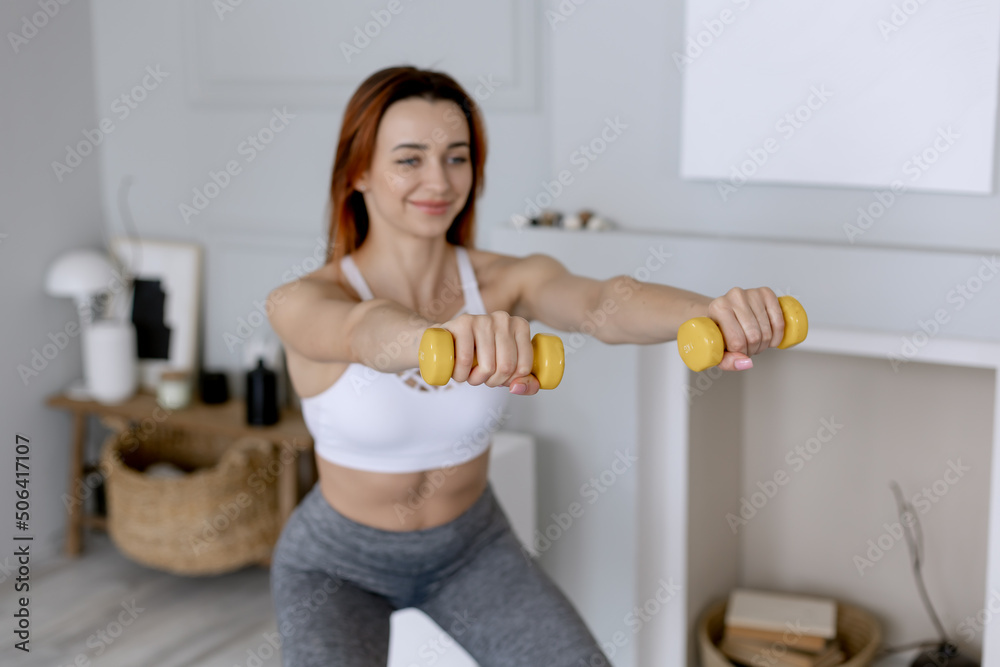 Young woman with a sports figure does exercises in the morning at home. Muscle exercises