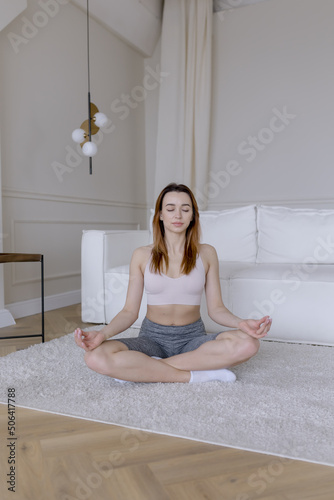 Woman meditating alone in sportswear at home
