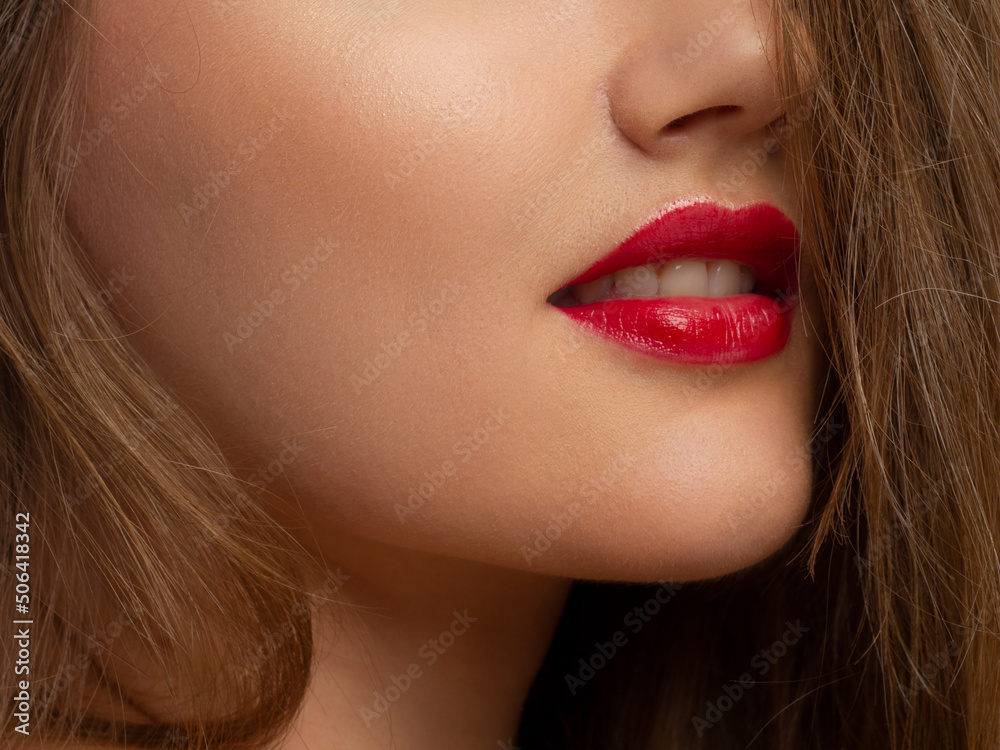 Fototapeta premium Macro photo of female lips with beautiful skin and nude makeup. light transparent gloss on full lips and white flowers. Fashion photography. Cosmetology and spa. Freshness of spring