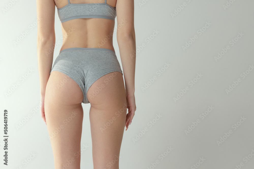 Cropped image of slim fit female body, buttocks in underwear isolated over grey studio background. Anti-cellulite care - obrazy, fototapety, plakaty 