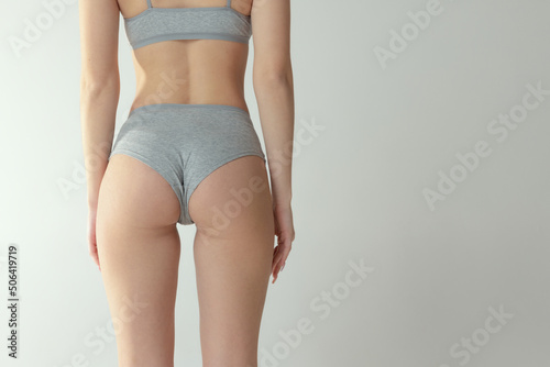 Cropped image of slim fit female body, buttocks in underwear isolated over grey studio background. Anti-cellulite care