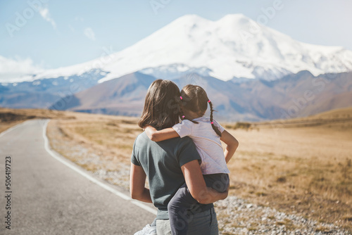 mother and daughter on a trip to the Caucasus, on a beautiful road jyly su in autumn against the backdrop of Mount Elbrus in Russia, stand with their backs, their faces are not visible